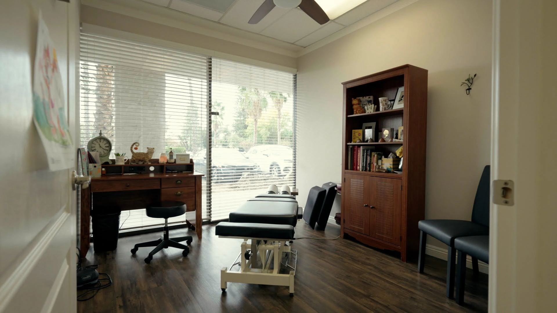Chiropractic office in Fresno with a treatment table, desk, and bookshelf