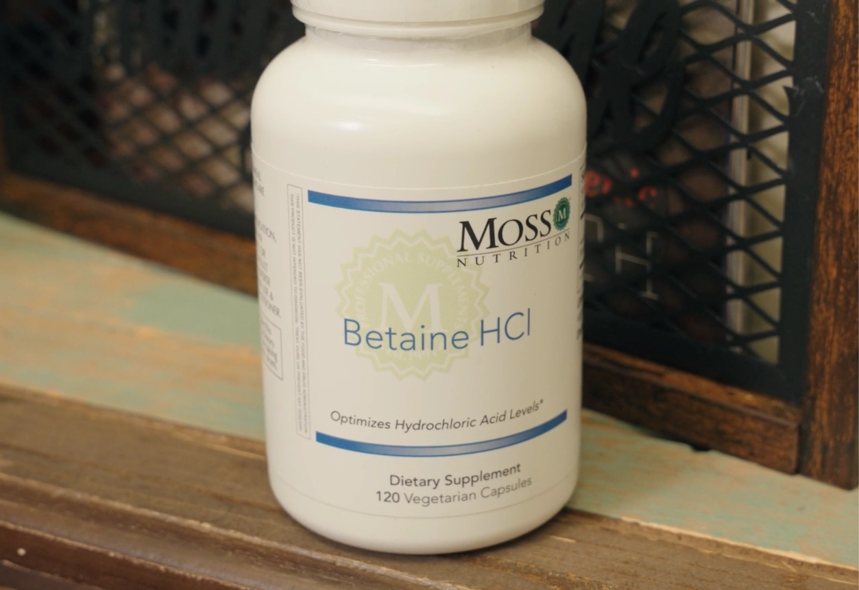 Bottle of Moss Nutrition Betaine HCl supplement on a wooden surface