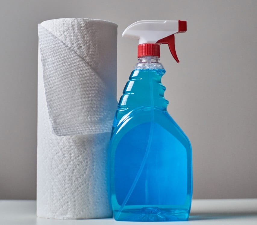 A roll of paper towels next to a spray bottle of blue cleaning solution