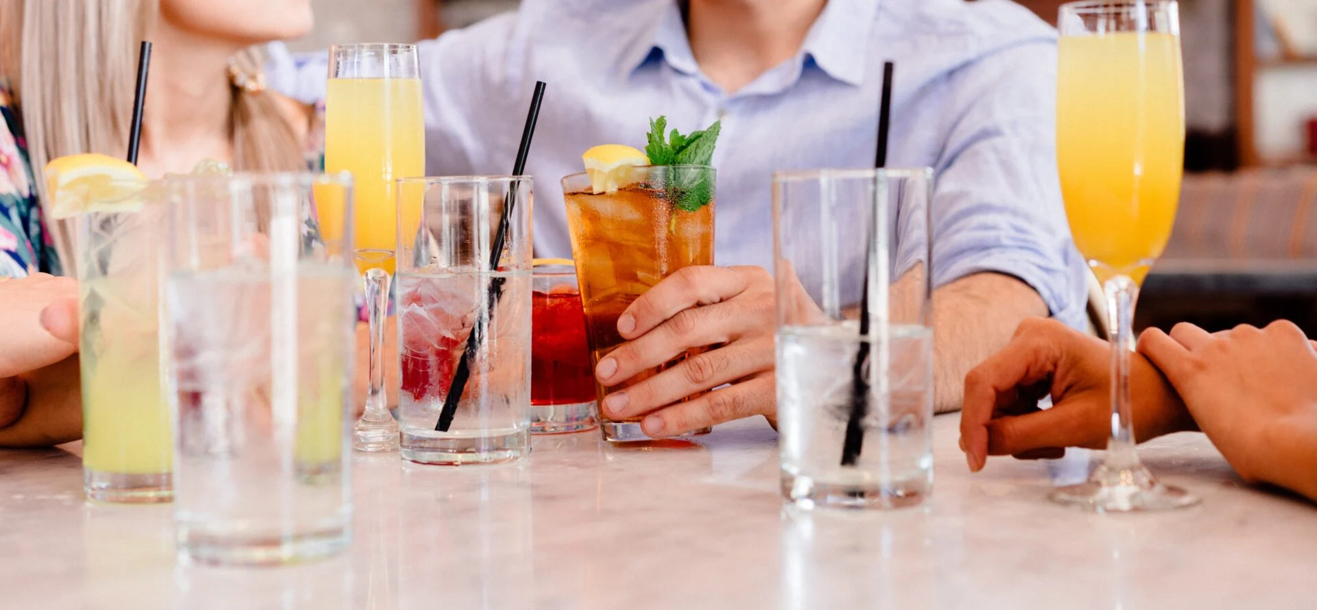 Assorted drinks in glasses on a bar including lemonade, iced tea and mimosas