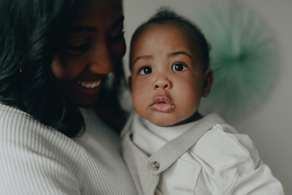 A woman smiling while holding a baby