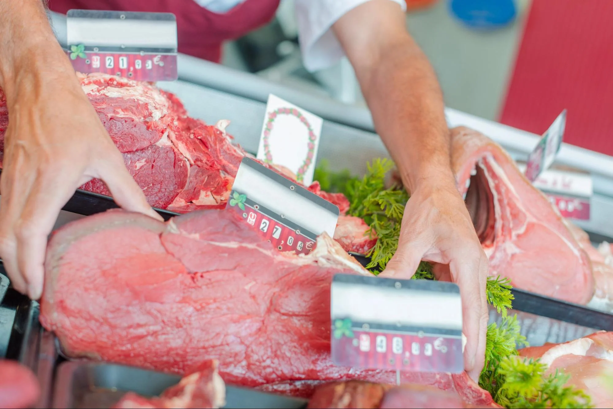 Butcher arranging fresh cuts of red meat at a market display