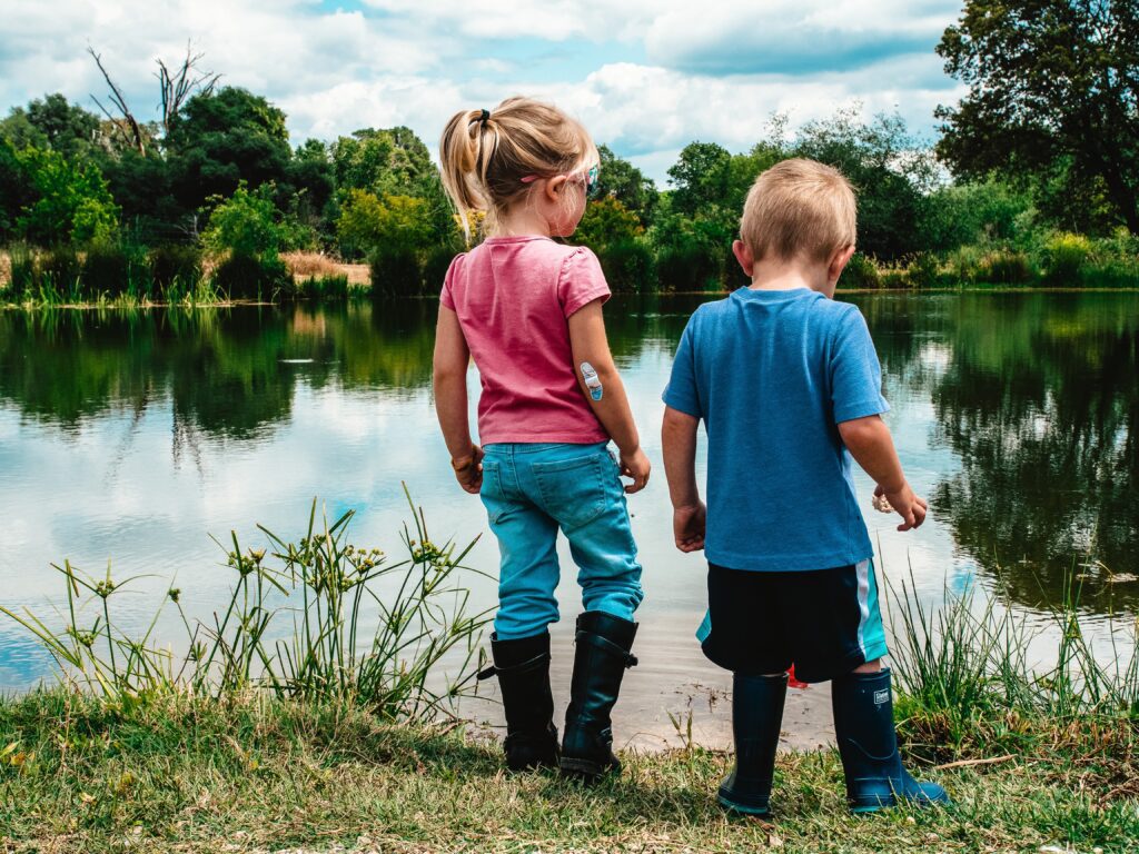 Image of a little girl and boy enjoying nature at a pond.